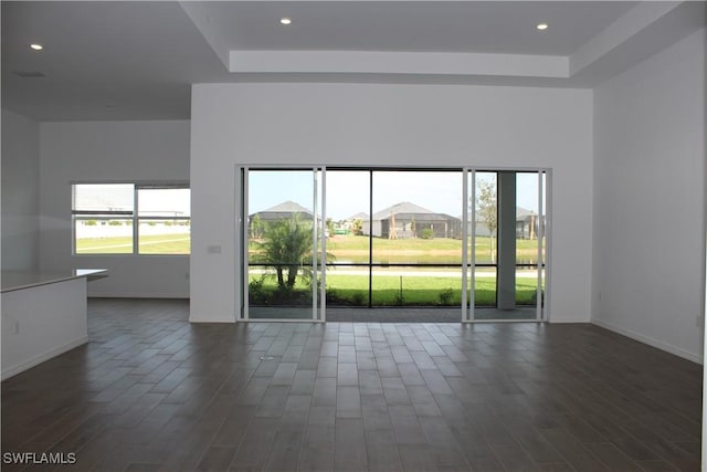 empty room with baseboards, a raised ceiling, and dark wood-type flooring