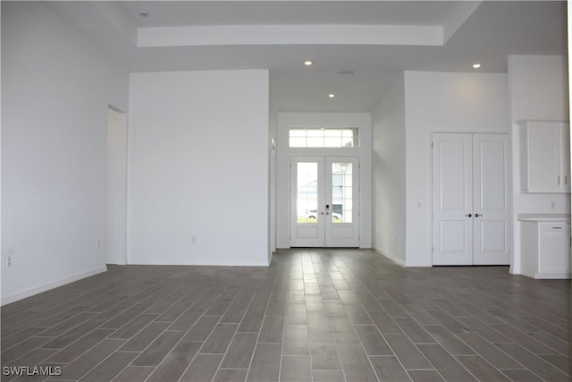 spare room with baseboards, a towering ceiling, dark wood-style flooring, french doors, and recessed lighting