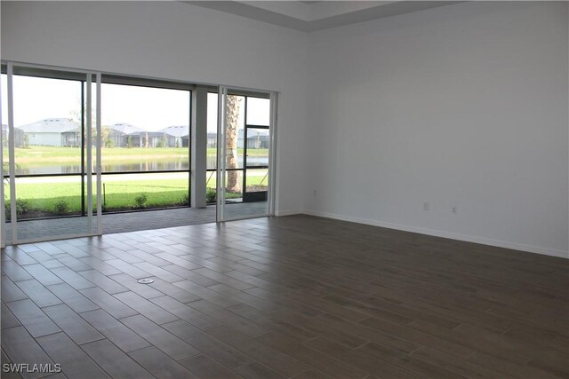 spare room with a residential view, dark wood finished floors, and baseboards