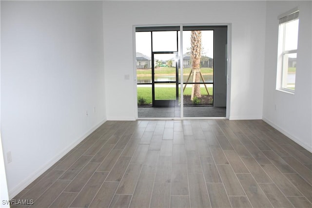 unfurnished room with a sunroom, baseboards, and wood finish floors