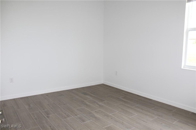 spare room featuring wood finish floors and baseboards