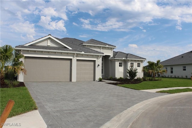 view of front facade with a front lawn, decorative driveway, a tile roof, and an attached garage