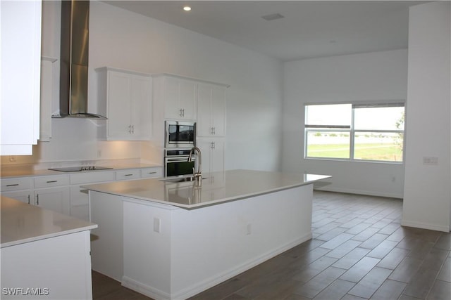 kitchen with stainless steel appliances, a sink, white cabinetry, light countertops, and wall chimney exhaust hood