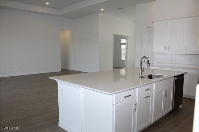 kitchen with wood finish floors, an island with sink, a sink, and white cabinets