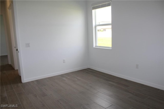 unfurnished room featuring dark wood-type flooring and baseboards