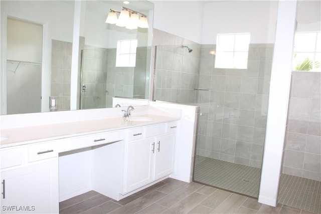 full bathroom featuring plenty of natural light, a sink, wood tiled floor, and a shower stall