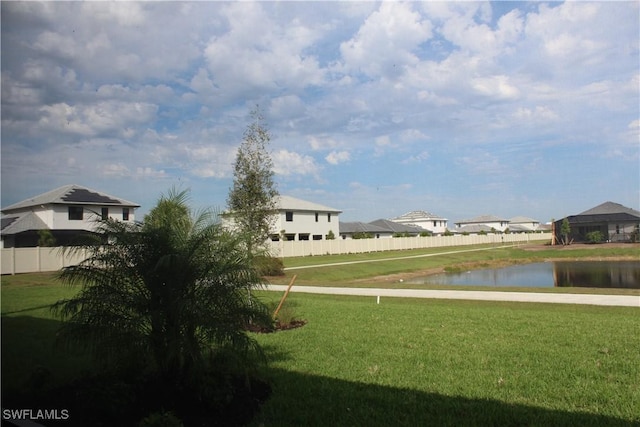 view of community with a yard, a water view, and fence