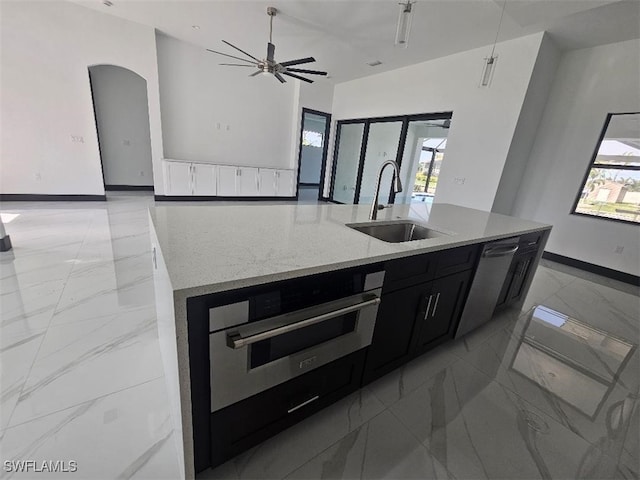 kitchen featuring a sink, stainless steel dishwasher, marble finish floor, and dark cabinetry