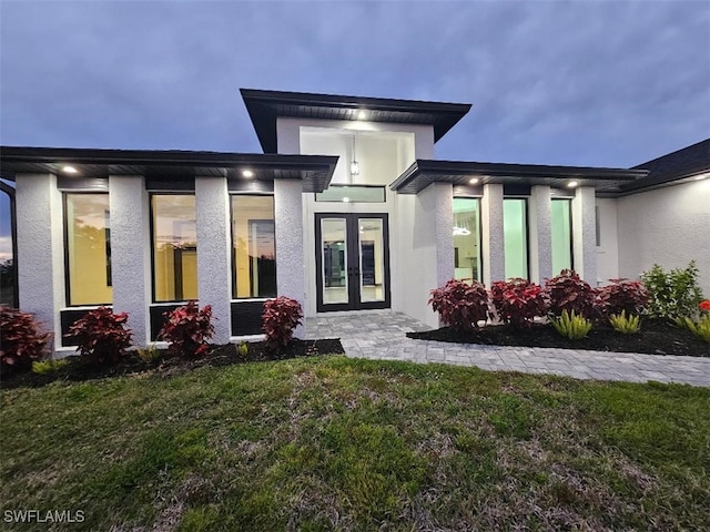 rear view of property featuring stucco siding and a lawn