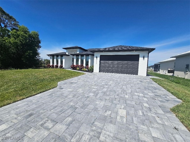 prairie-style house with stucco siding, an attached garage, decorative driveway, and a front yard