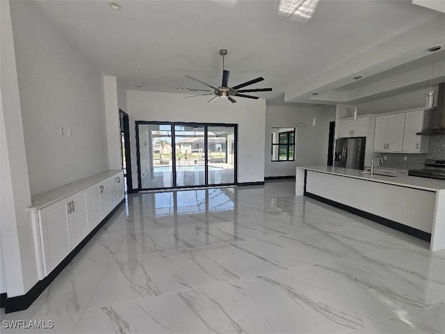 unfurnished living room featuring a wealth of natural light, marble finish floor, and a sink