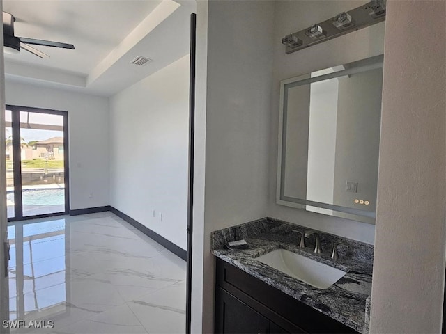 bathroom with baseboards, ceiling fan, marble finish floor, vanity, and a raised ceiling