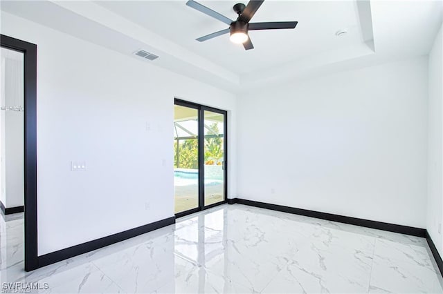 unfurnished room with visible vents, a raised ceiling, and baseboards