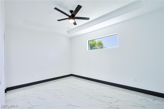 spare room featuring baseboards, a raised ceiling, marble finish floor, and ceiling fan