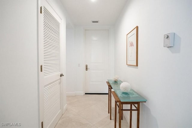 hall featuring visible vents, baseboards, and light tile patterned floors