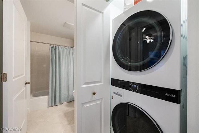 clothes washing area with laundry area, light tile patterned flooring, and stacked washer and clothes dryer