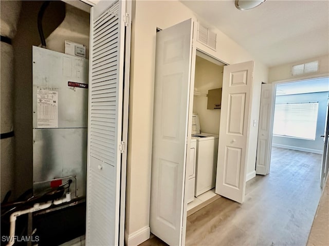 kitchen featuring visible vents, baseboards, washing machine and clothes dryer, heating unit, and light wood-style floors