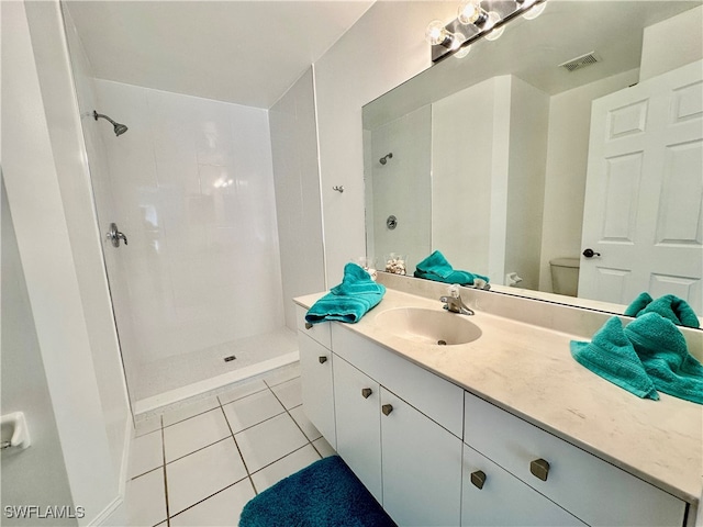 bathroom with visible vents, a tile shower, and vanity