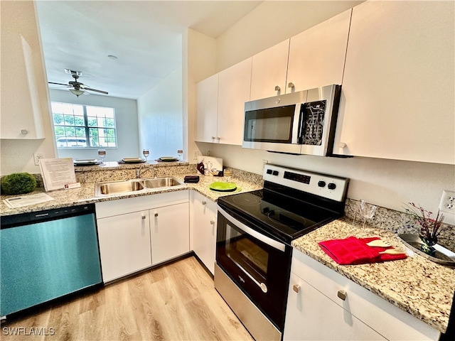 kitchen featuring stainless steel appliances, light wood-style floors, white cabinetry, a sink, and ceiling fan