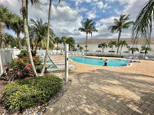 pool with a patio area and fence