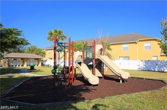 community jungle gym featuring a lawn and fence