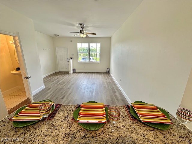 interior space featuring a ceiling fan, baseboards, and wood finished floors