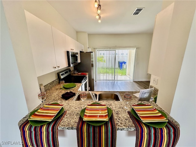 kitchen featuring white cabinets, visible vents, stainless steel appliances, and track lighting