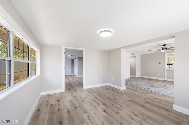 unfurnished room with a ceiling fan, light wood-type flooring, and baseboards