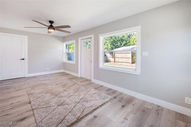 interior space with light wood finished floors, a ceiling fan, and baseboards