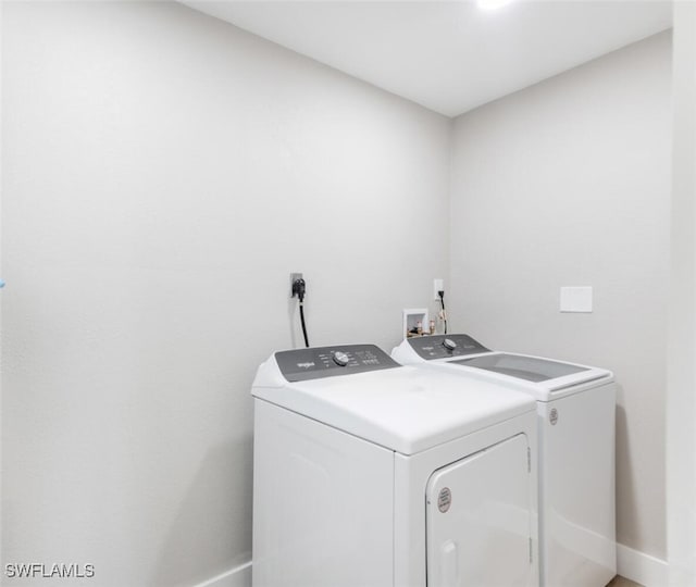 laundry room with laundry area, washing machine and dryer, and baseboards