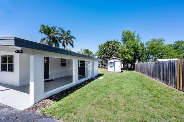 view of yard with a patio, an outdoor structure, a storage unit, and fence