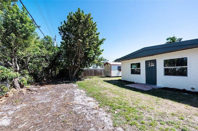 view of yard with an outbuilding, fence, and a storage shed