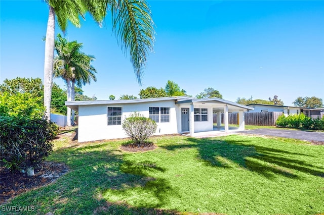 view of front of property with a front yard, fence, driveway, and stucco siding