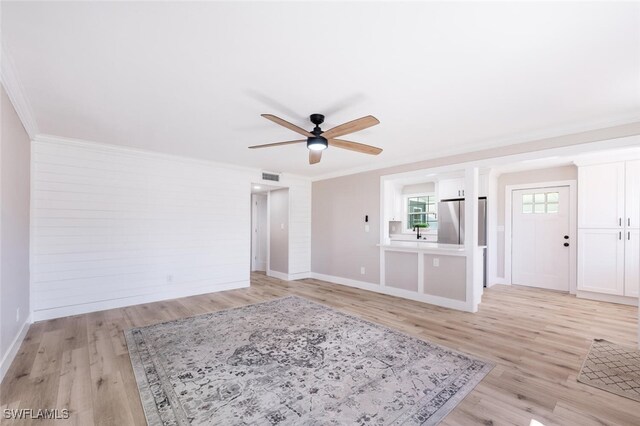 unfurnished living room with light wood-style flooring, visible vents, ornamental molding, and a ceiling fan