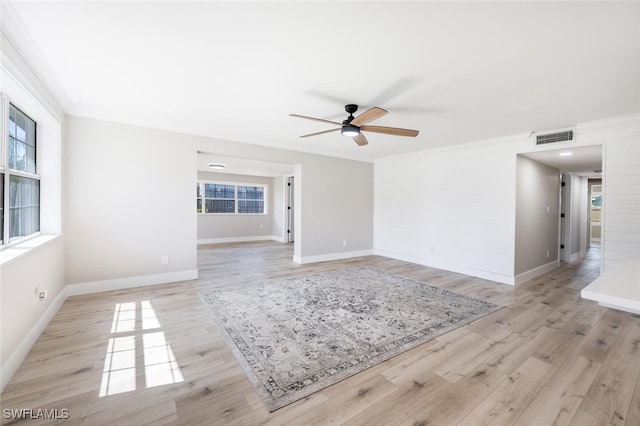 spare room featuring a healthy amount of sunlight, light wood finished floors, visible vents, and ornamental molding