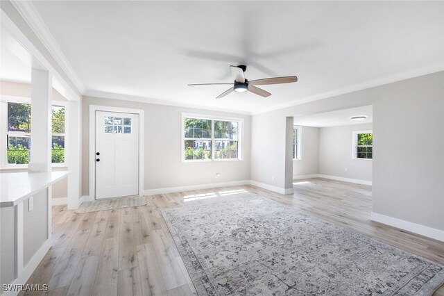 foyer entrance with a healthy amount of sunlight, light wood-type flooring, baseboards, and crown molding