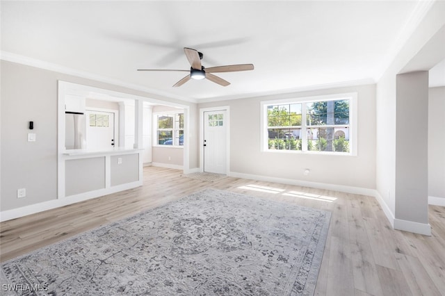 unfurnished living room with light wood-style floors, a ceiling fan, baseboards, and crown molding