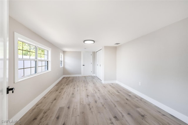 spare room featuring light wood-type flooring, visible vents, and baseboards