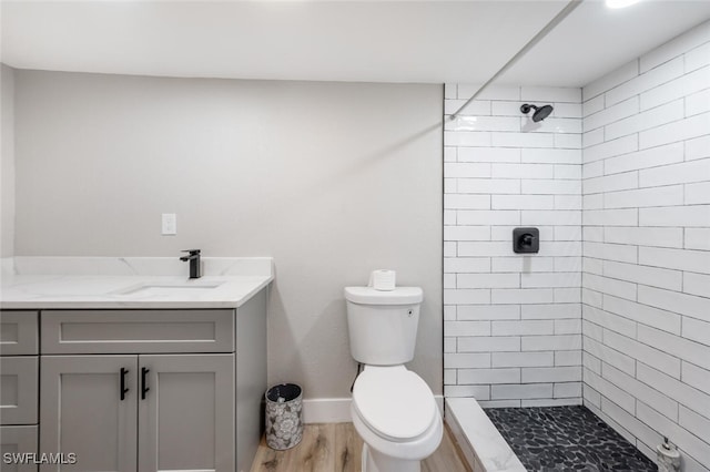 full bath with a stall shower, baseboards, toilet, wood finished floors, and vanity