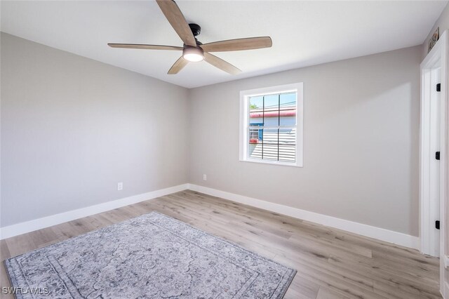 spare room featuring light wood-style floors, baseboards, and a ceiling fan