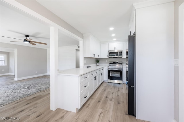 kitchen with white cabinets, light wood finished floors, appliances with stainless steel finishes, and light countertops