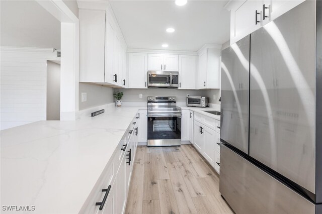 kitchen with white cabinets, appliances with stainless steel finishes, light stone countertops, light wood-type flooring, and recessed lighting