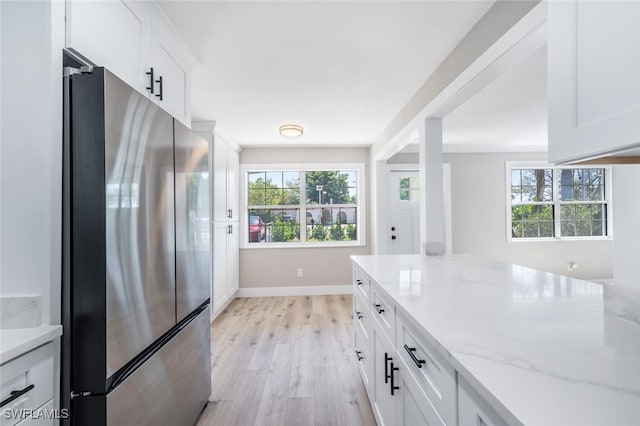 kitchen featuring a wealth of natural light, freestanding refrigerator, white cabinets, and light wood-style flooring