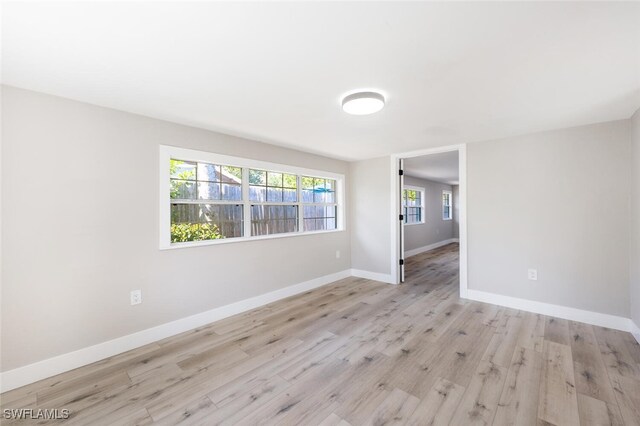 spare room with baseboards and wood finished floors