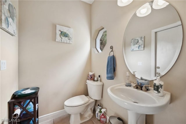 bathroom featuring toilet, tile patterned floors, a sink, and baseboards