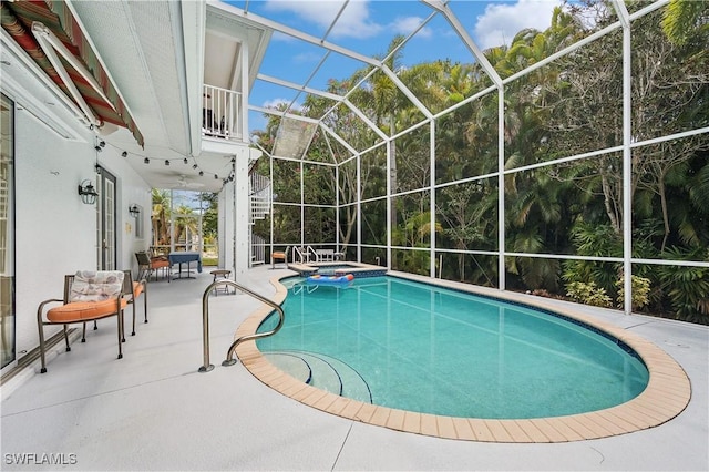 view of swimming pool featuring a patio area, a pool with connected hot tub, and a lanai