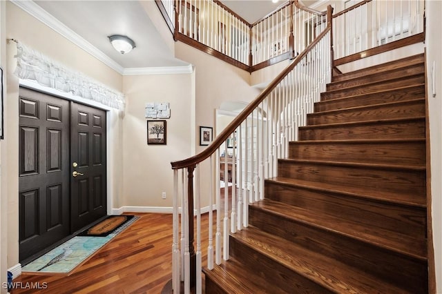 foyer with stairway, baseboards, crown molding, and wood finished floors