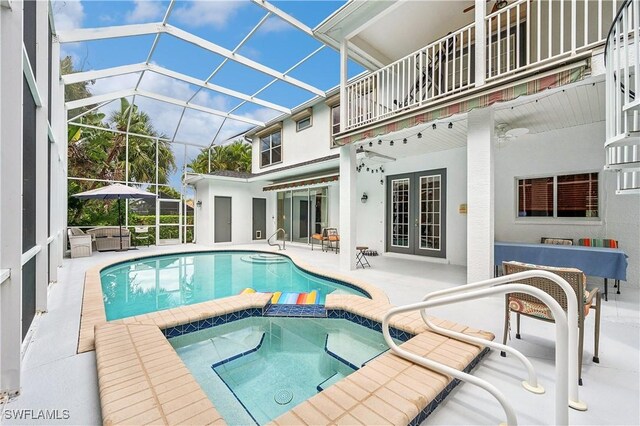 view of pool featuring a patio area, french doors, a pool with connected hot tub, and a lanai