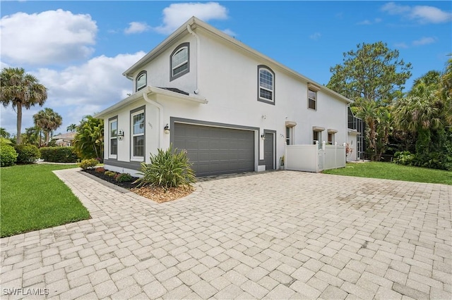 view of home's exterior with a yard, decorative driveway, a garage, and stucco siding