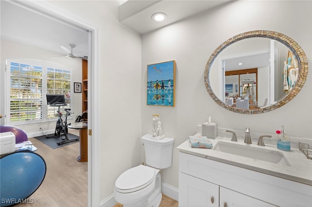 bathroom featuring baseboards, toilet, wood finished floors, vanity, and recessed lighting